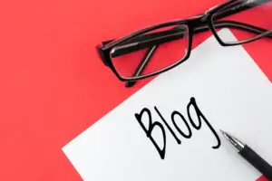 Reading glasses and blank with inscription blog on a red background