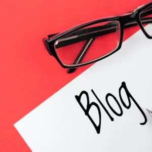 Reading glasses and blank with inscription blog on a red background