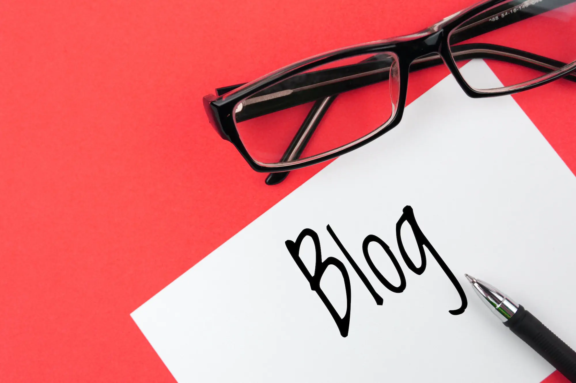 Reading glasses and blank with inscription blog on a red background